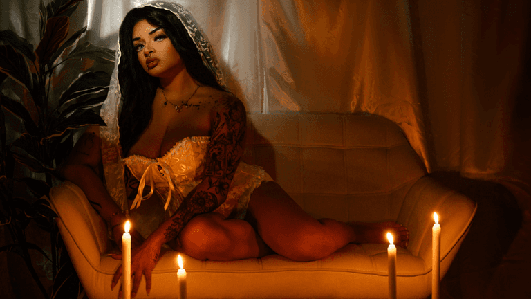 "Anastasia Artemiou seated in a soft, mystical setting, representing her spiritual brand The Manifestation Doll focused on magick, healing, and mindset work."