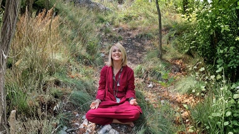 A serene Dr. Antonia Califano meditating in nature, embodying personal transformation, resilience, and self-discovery amidst a peaceful landscape.