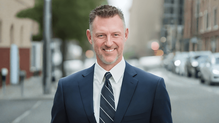 Cameron Oxberry, Divorce Mortgage Expert, smiling in a professional suit on an urban street.