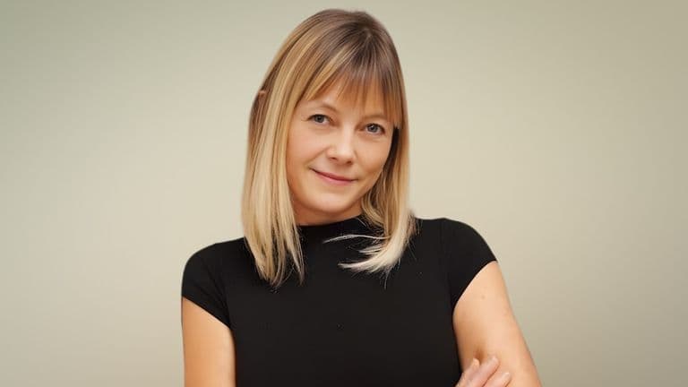 Kori Burkholder, career clarity coach, smiling confidently in a black shirt, with a neutral background, embodying empowerment.