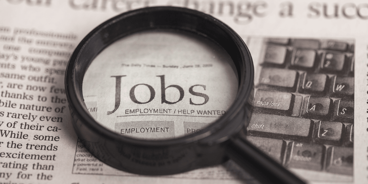 Magnifying glass over a newspaper page highlighting job listings and employment opportunities
