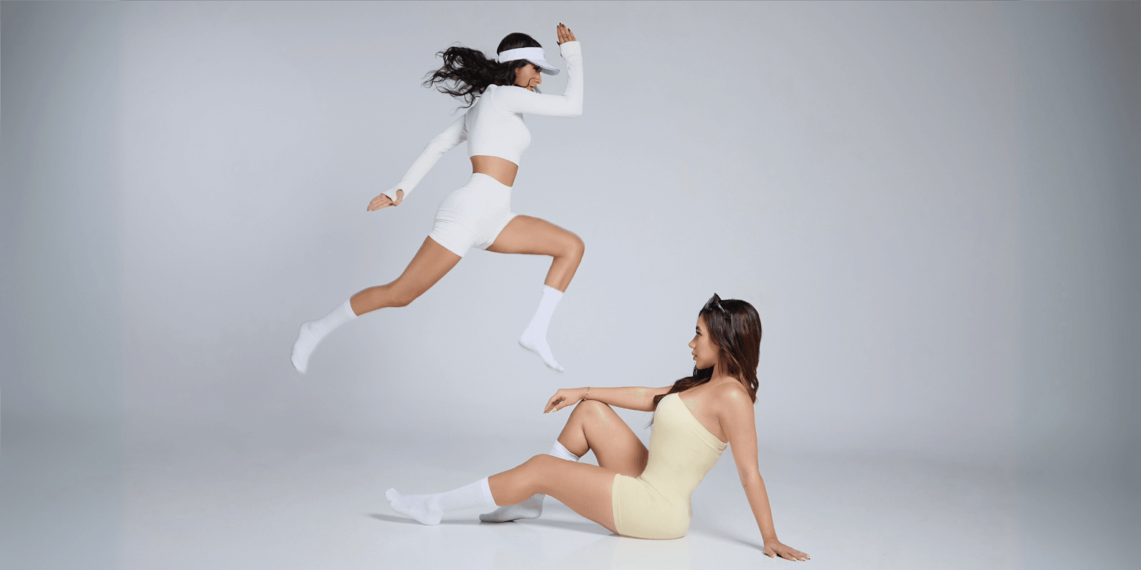 Two women in athletic wear pose dynamically, showcasing Fit N Sip Live’s fusion of fitness, AI coaching, and cultural experiences to empower women in their wellness and leadership journeys.