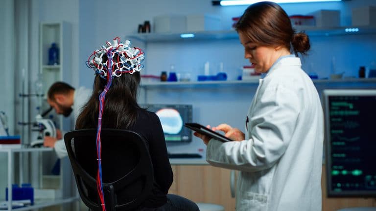 Back View Woman Patient Wearing Performant Eeg Headset Sitting Chair Neurological Research Laboratory While Medical Researcher Adjusting It Examining Nervous System Typing Tablet 482257 13106