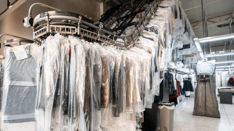 Clothes on hangers covered in plastic in a dry cleaning facility interior