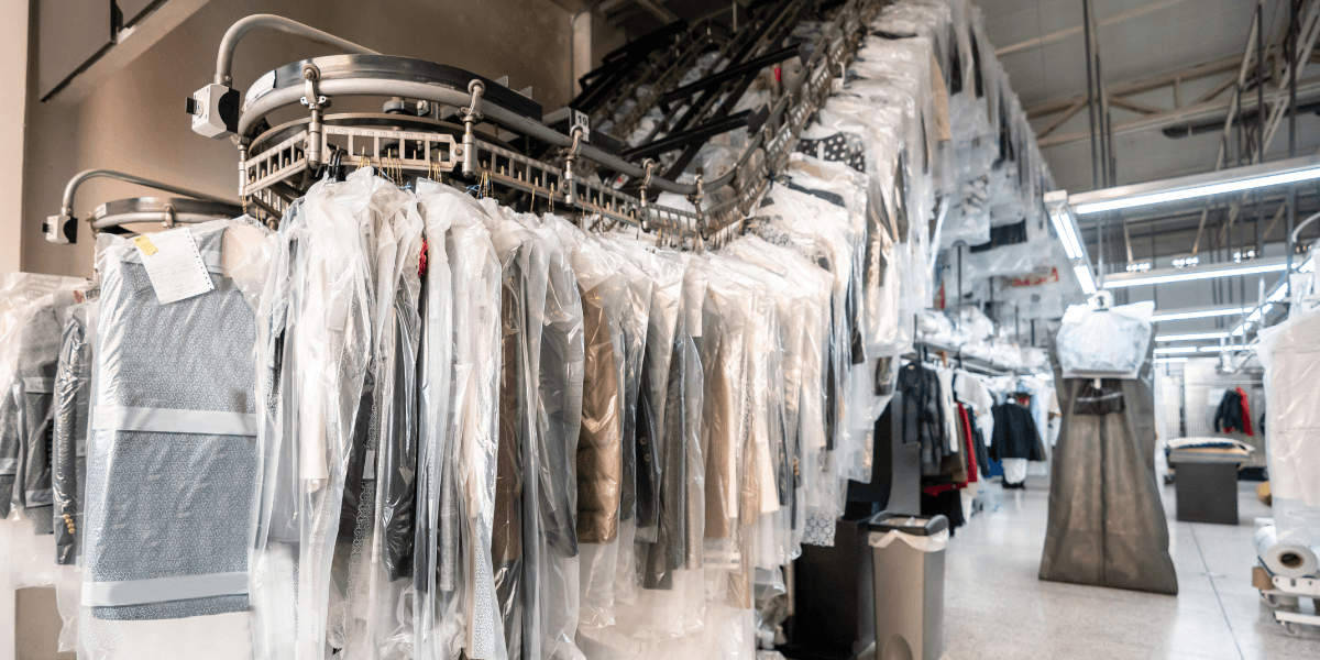 Clothes on hangers covered in plastic in a dry cleaning facility interior