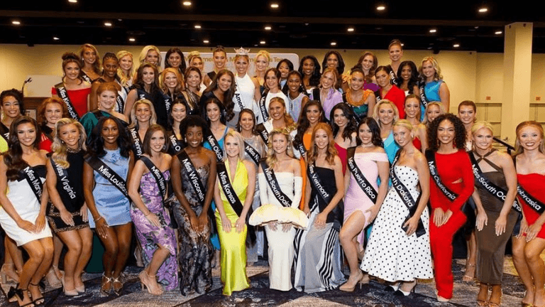 Group photo of contestants in evening gowns at a pageant event on stage