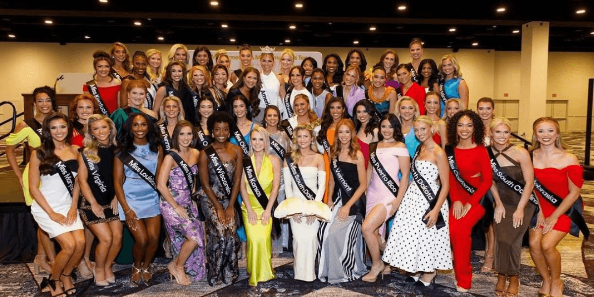 Group photo of contestants in evening gowns at a pageant event on stage