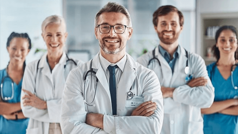 A diverse group of five healthcare professionals smiling confidently in a hospital setting