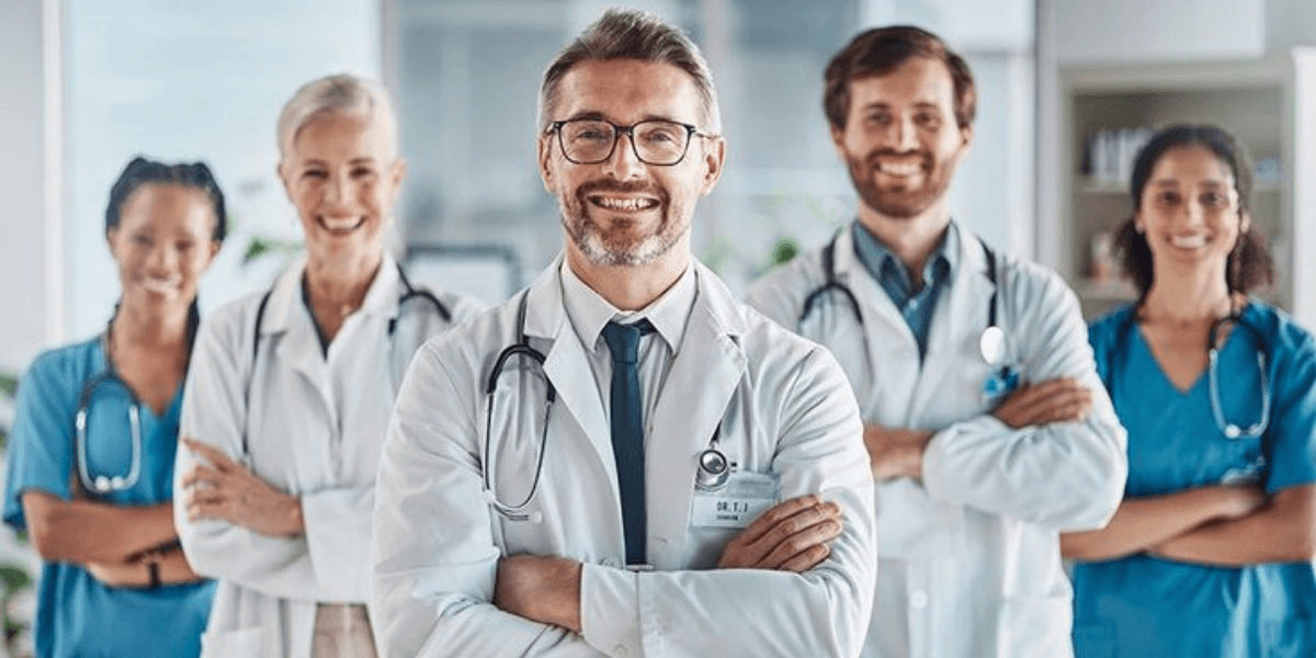 A diverse group of five healthcare professionals smiling confidently in a hospital setting
