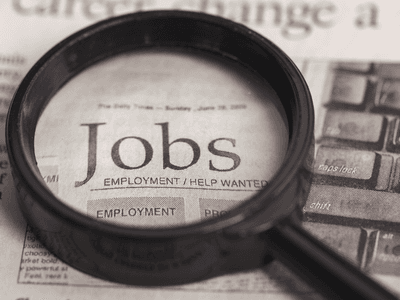Magnifying glass over a newspaper page highlighting job listings and employment opportunities