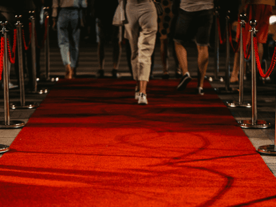 People walking down a red carpet lined with shiny stanchions and ropes