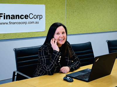 Woman talking on the phone seated at a desk with a laptop and company banner
