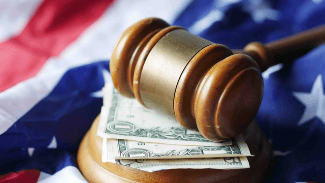 Gavel resting on dollar bills atop a folded American flag