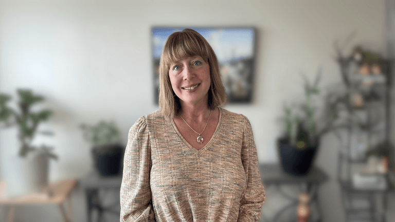 Traci Griffin, founder of Elevate 50+, standing confidently in a cozy space, embodying the resilience and purpose of the brand.