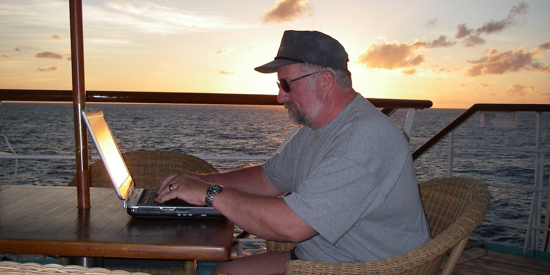 Baer Charlton writing on a laptop aboard a ship at sunset.