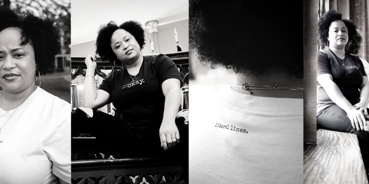 A woman with afro hair sits on a chair, wearing a minimalist tee from Literal Lines., embodying authentic storytelling.