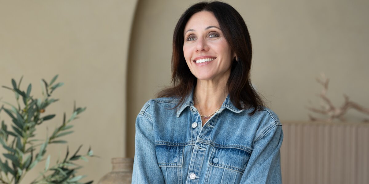 A smiling woman in a denim jacket, embodying confidence and empowerment in midlife wellness.
