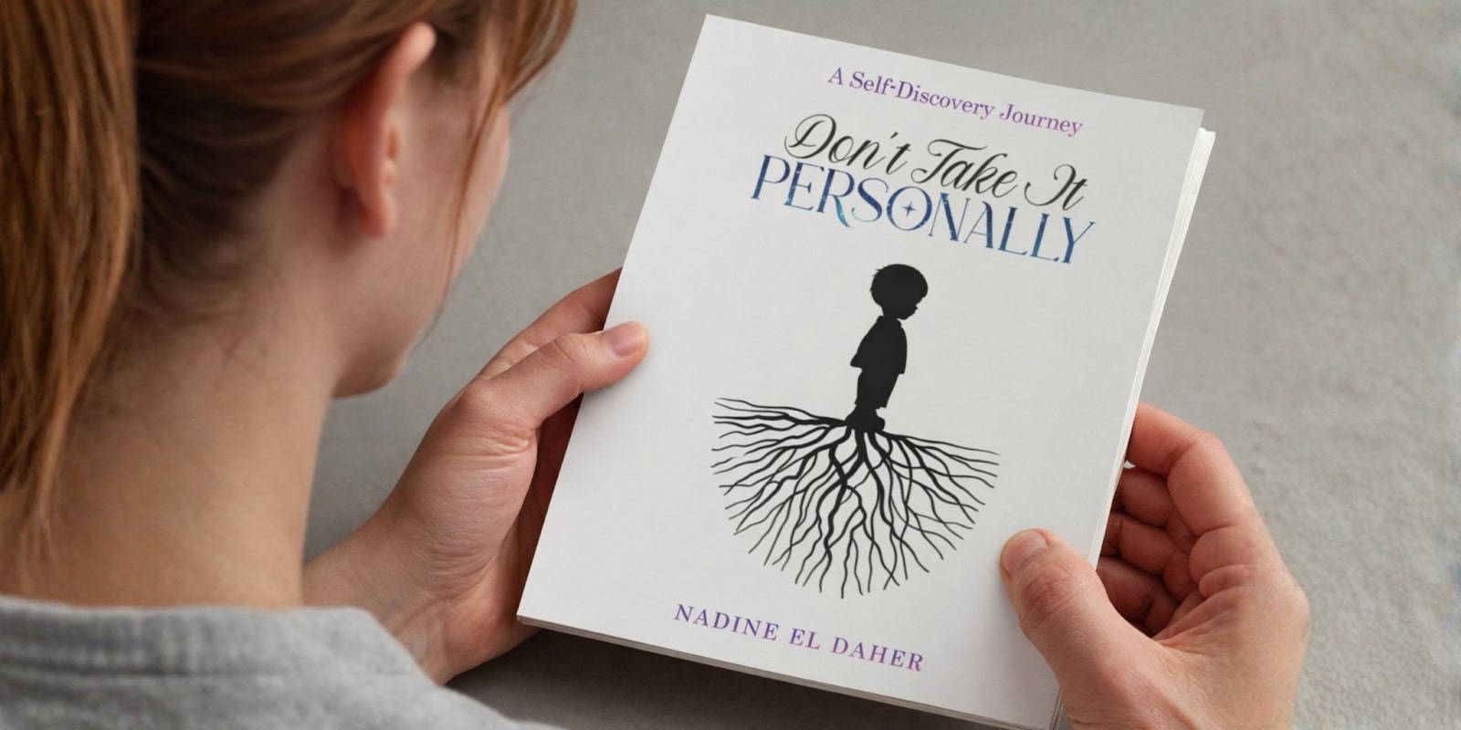 A person holding the book "Don't Take It Personally" by Nadine El Daher, with the book’s cover visible.
