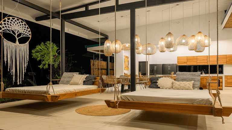 A serene wellness retreat featuring wooden swing beds, hanging lights, and nature-inspired decor, blending Pilates and nature immersion.