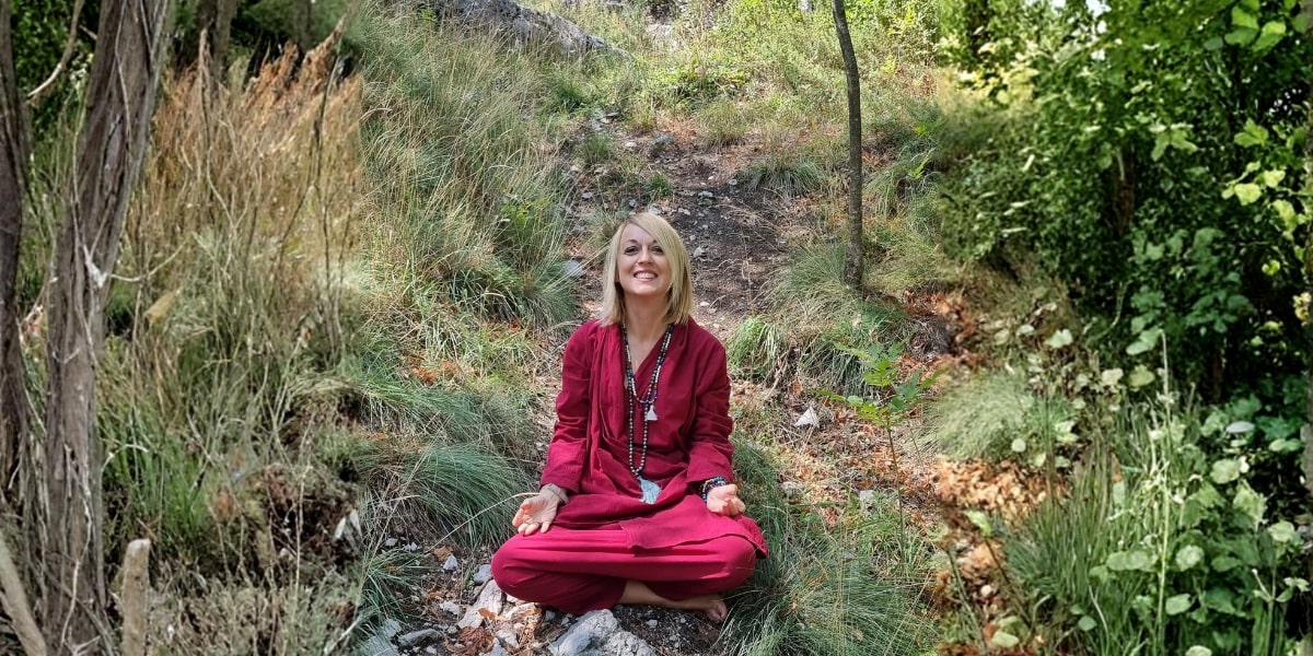 A serene Dr. Antonia Califano meditating in nature, embodying personal transformation, resilience, and self-discovery amidst a peaceful landscape.