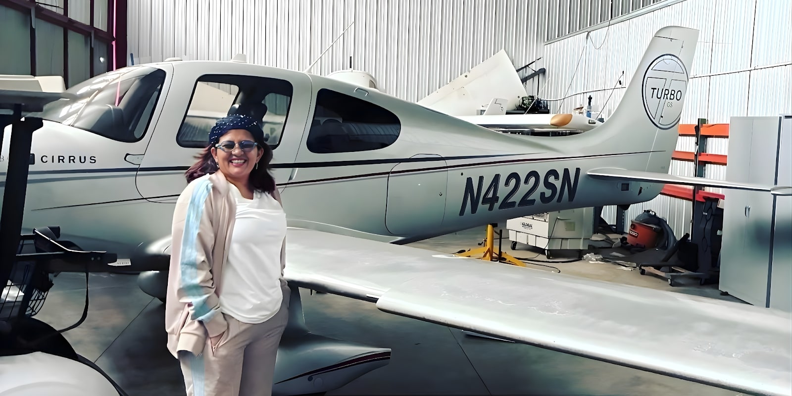 Isha Chhabra, President of GlobalGlowFilms, standing beside a Cirrus aircraft, embodying the brand's global lifestyle ethos.