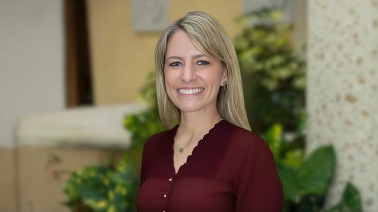 A woman with blonde hair wearing a maroon shirt, smiling and embodying creativity and inspiration for children’s adventures.