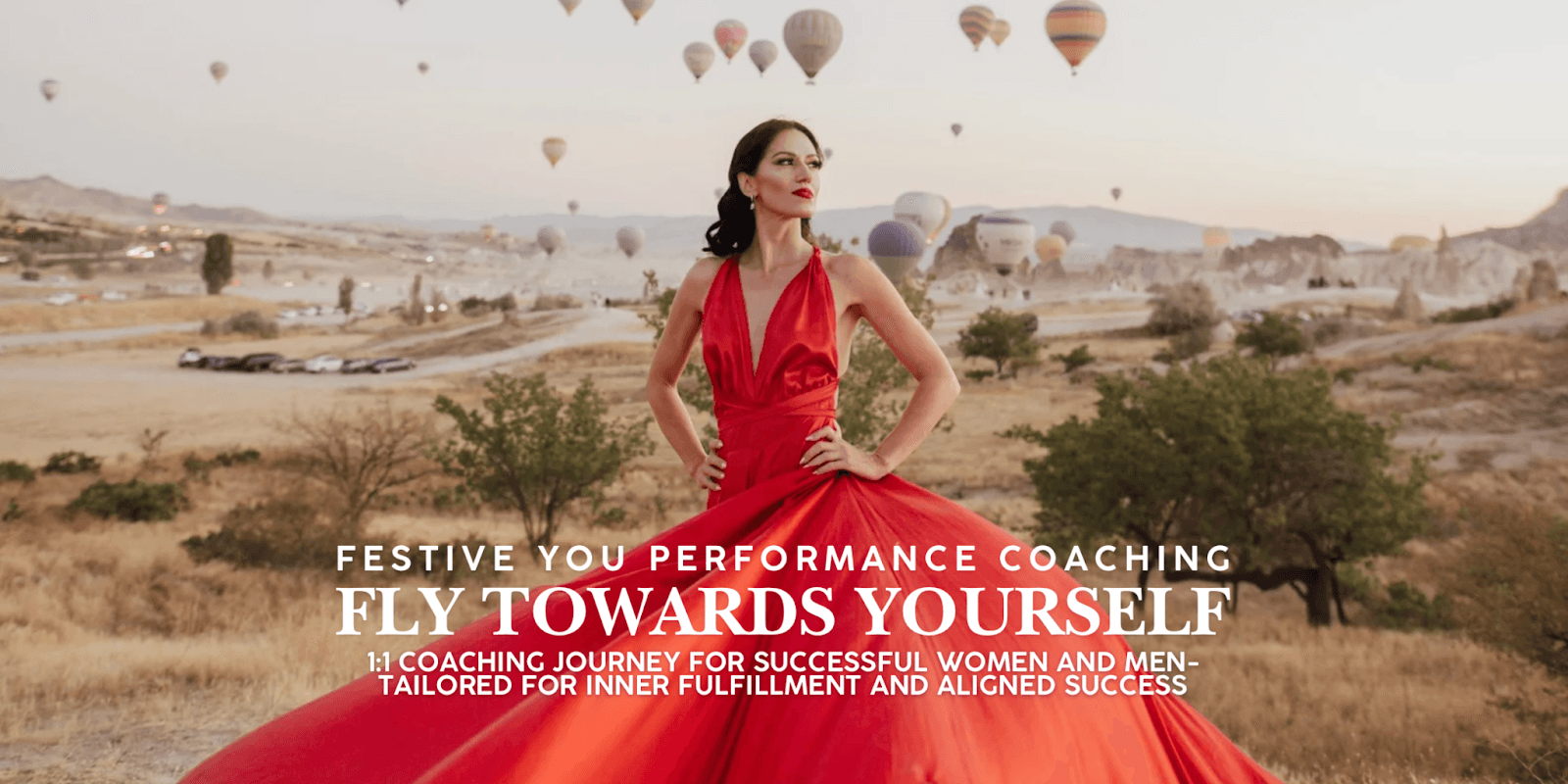 Woman in flowing red dress stands confidently with hot air balloons in the background at sunrise.