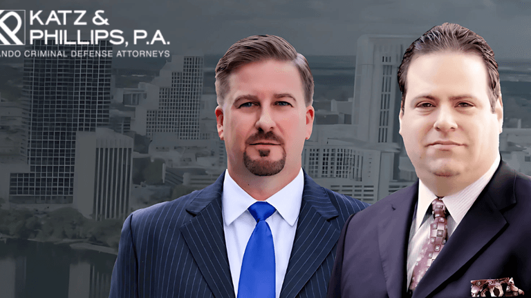 Two suited men in front of a city skyline with the Katz & Phillips, P.A. logo above them.