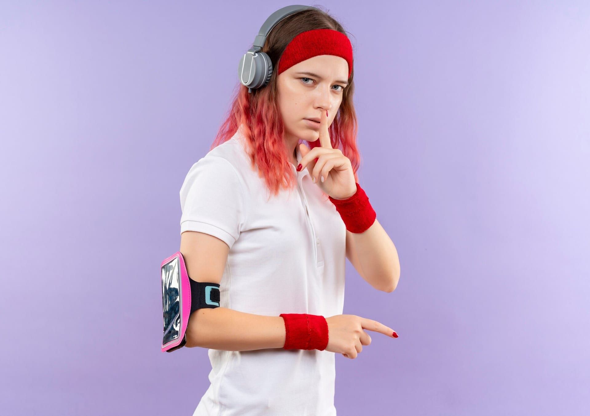 Young Sporty Woman Headband With Headphones Making Silence Gesture With Finger Lips Standing Purple Wall 141793 50260