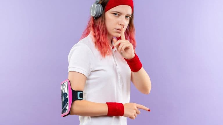 Young Sporty Woman Headband With Headphones Making Silence Gesture With Finger Lips Standing Purple Wall 141793 50260