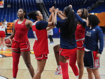 Female basketball players celebrating together on the court during practice session